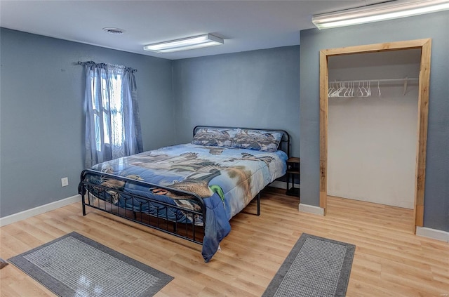 bedroom featuring baseboards, a closet, visible vents, and wood finished floors