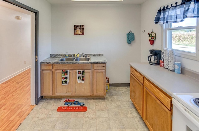 kitchen featuring baseboards and a sink