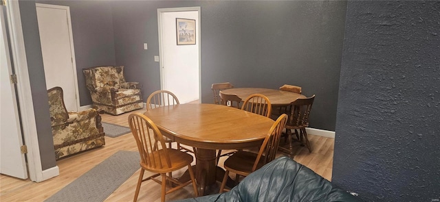 dining room with light wood-type flooring, baseboards, and a textured wall