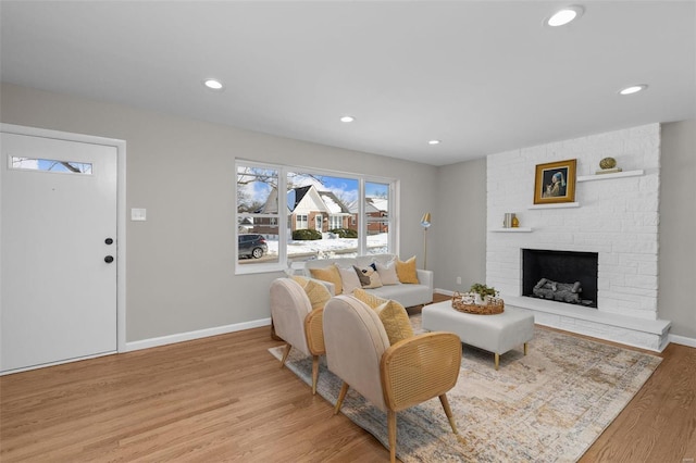 living room with a brick fireplace and light hardwood / wood-style flooring