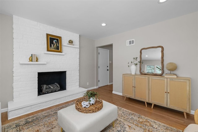 living room featuring a brick fireplace and light hardwood / wood-style floors