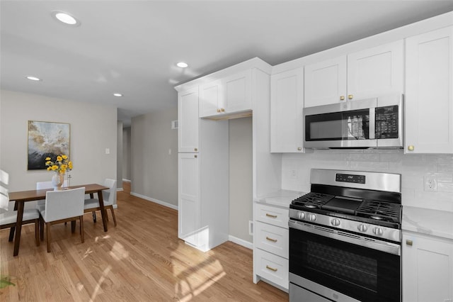 kitchen featuring backsplash, appliances with stainless steel finishes, light stone counters, and white cabinetry