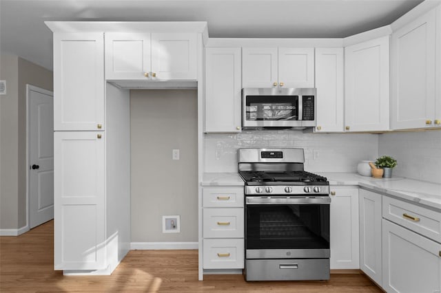 kitchen with light stone countertops, white cabinets, and appliances with stainless steel finishes