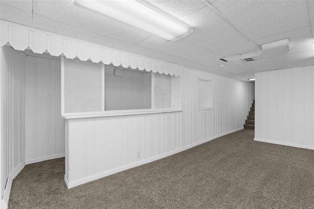 empty room with a paneled ceiling and dark colored carpet