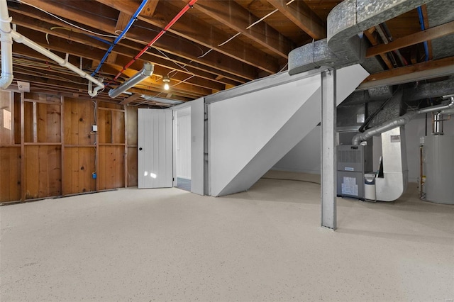 basement with wood walls, heating unit, and gas water heater