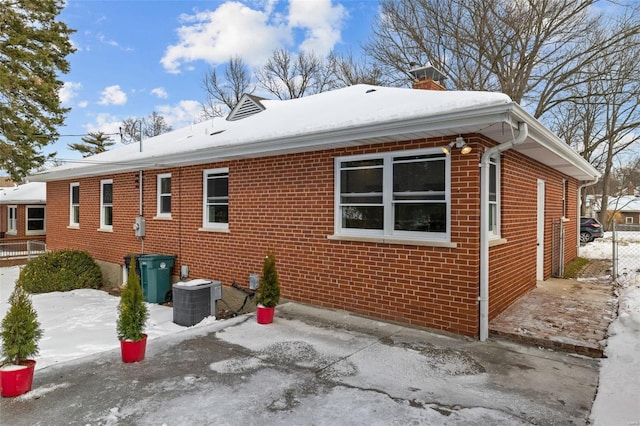 view of snow covered exterior with central AC unit