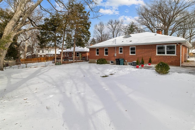 snow covered back of property with central AC