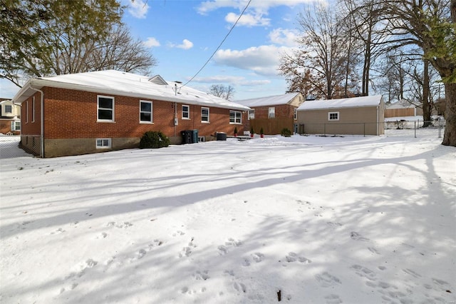 snow covered back of property with a storage shed