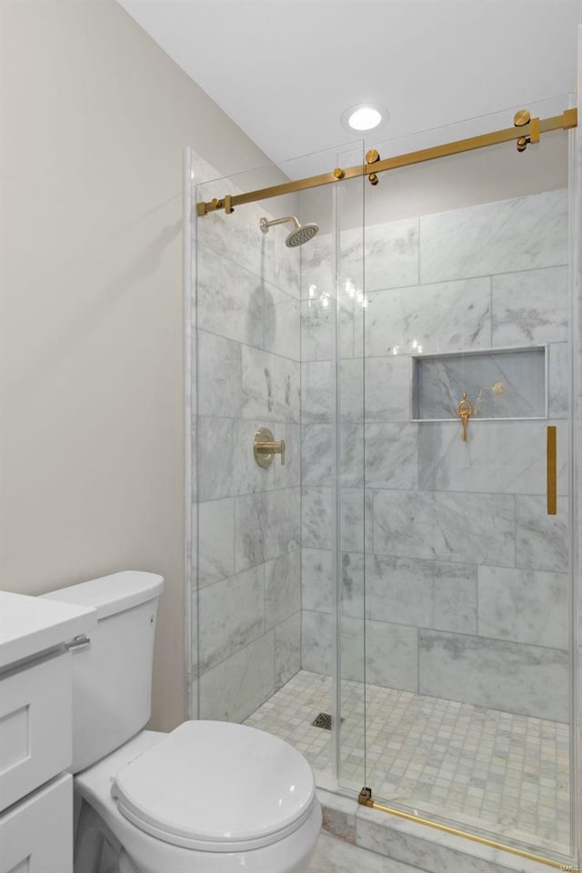 bathroom featuring toilet, a shower with door, and vanity