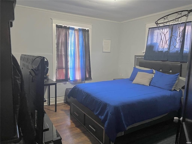 bedroom with hardwood / wood-style floors, baseboard heating, and crown molding