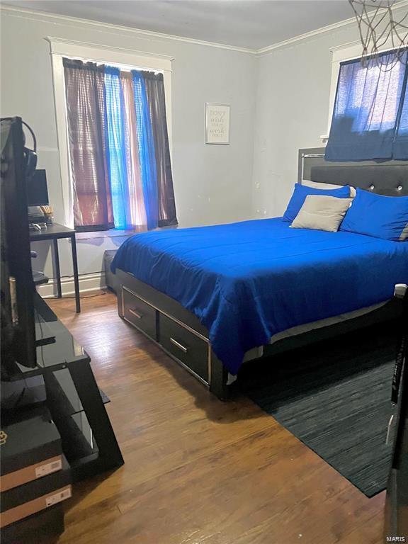 bedroom with wood-type flooring and crown molding