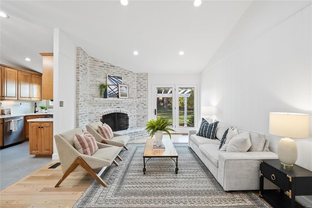 living room with light hardwood / wood-style floors, a fireplace, and vaulted ceiling