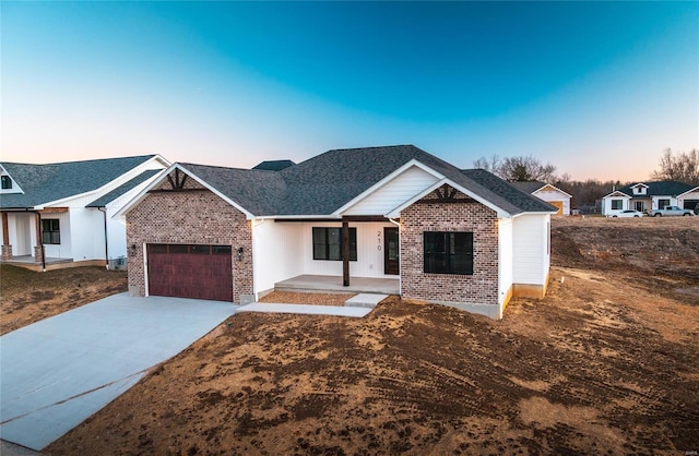 view of front facade with an attached garage, a porch, concrete driveway, and brick siding