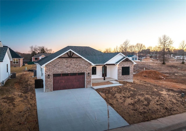 view of front of home featuring driveway, a garage, covered porch, cooling unit, and brick siding