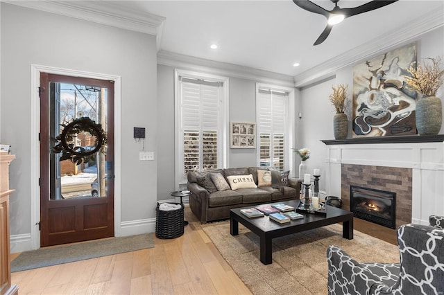 living room featuring ornamental molding, ceiling fan, a fireplace, and wood-type flooring