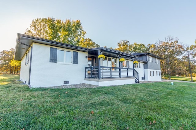 rear view of property with covered porch and a yard