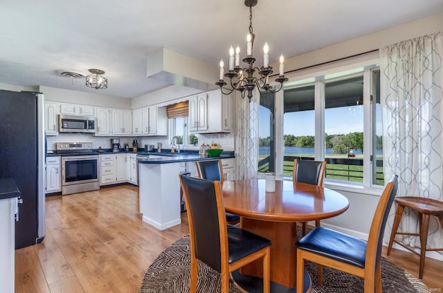 dining area featuring light hardwood / wood-style floors, sink, and an inviting chandelier