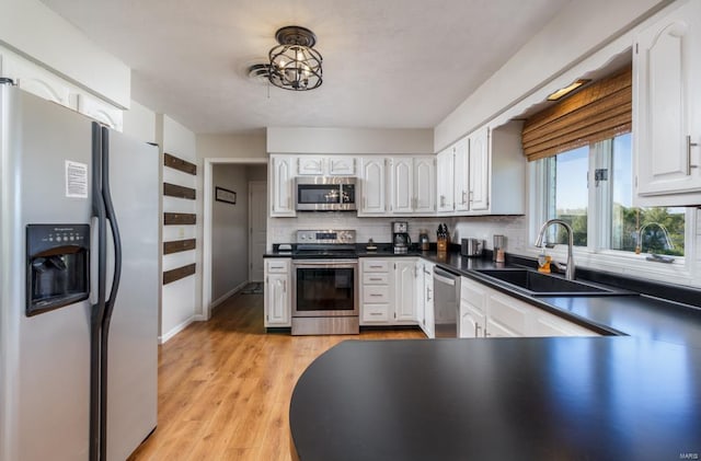 kitchen featuring white cabinetry, sink, stainless steel appliances, tasteful backsplash, and light hardwood / wood-style flooring