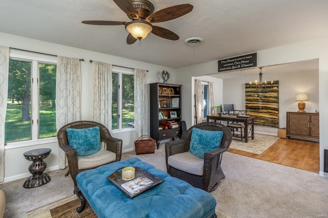 sitting room featuring carpet and ceiling fan with notable chandelier