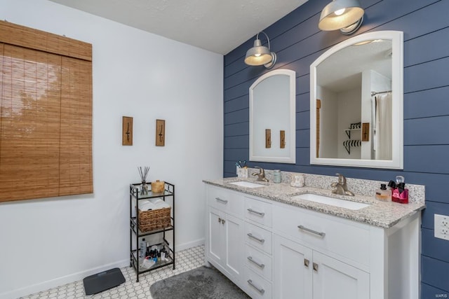 bathroom with tile patterned floors, vanity, wood walls, and a textured ceiling