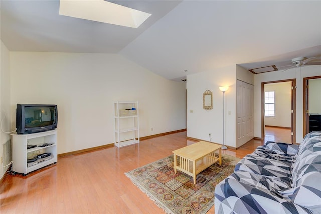 living room with ceiling fan, hardwood / wood-style floors, and lofted ceiling with skylight