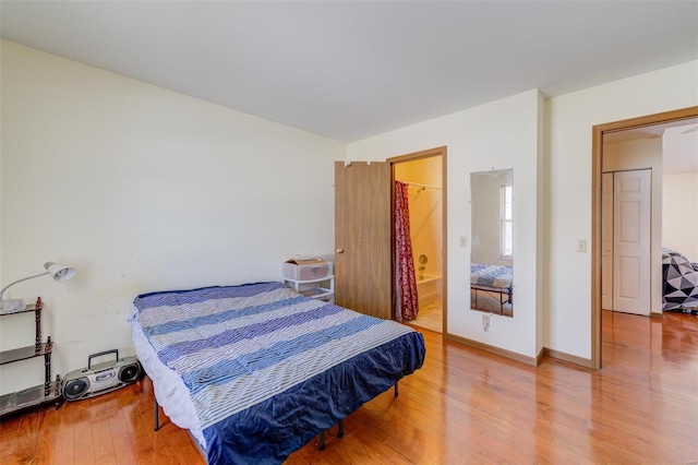 bedroom featuring ensuite bath and hardwood / wood-style floors