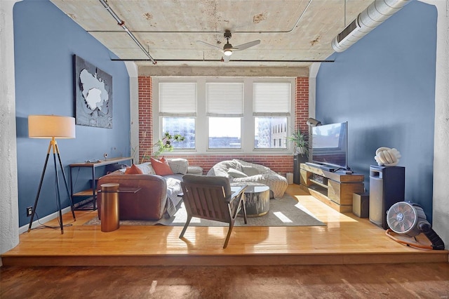 sitting room with ceiling fan and brick wall