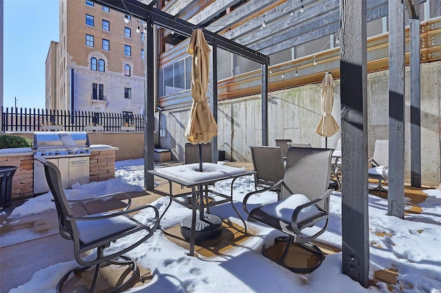 snow covered patio featuring a grill, an outdoor kitchen, and a pergola