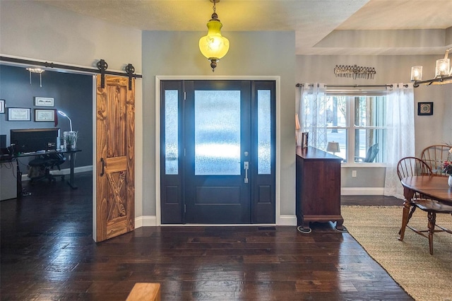 foyer entrance with a raised ceiling, a barn door, and dark hardwood / wood-style floors