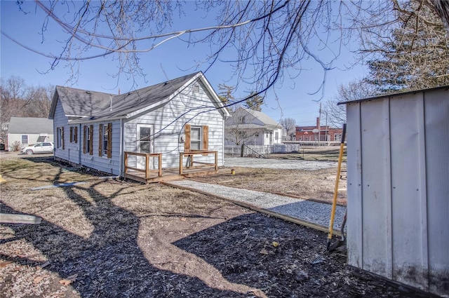 exterior space featuring a shingled roof, fence, and a deck