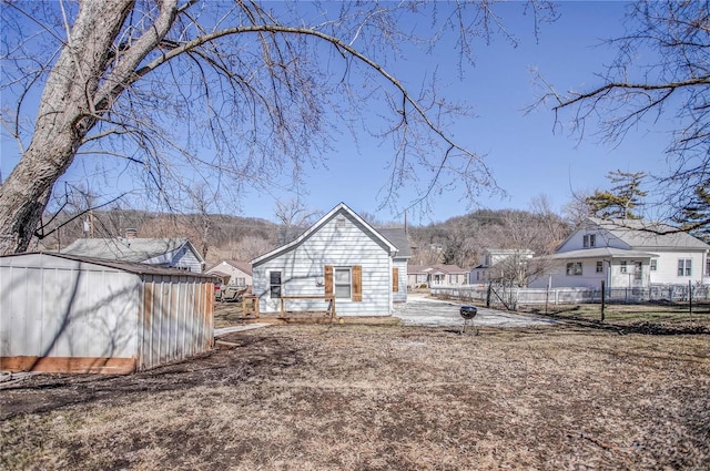 back of house with a shed, an outdoor structure, and fence