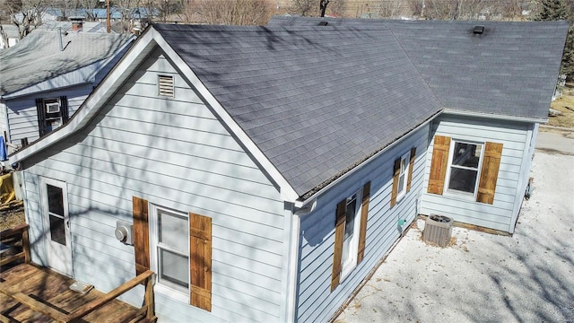 view of property exterior featuring a shingled roof and central AC