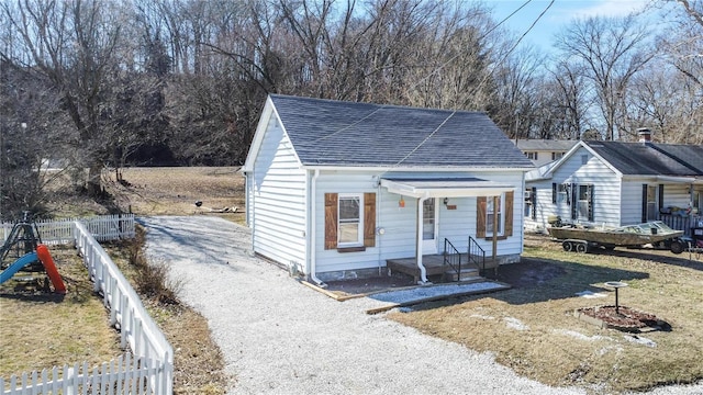 view of front of property featuring driveway, a shingled roof, and fence