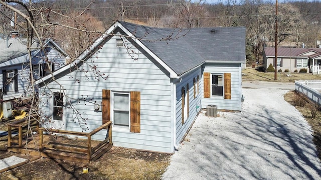 exterior space with a shingled roof and central AC