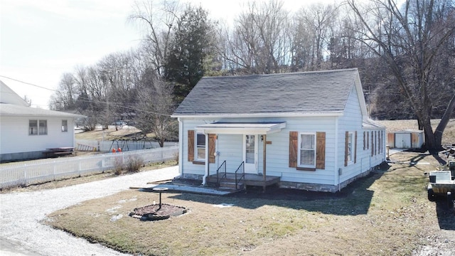 view of front of home featuring a shingled roof, an outbuilding, fence, and a storage unit