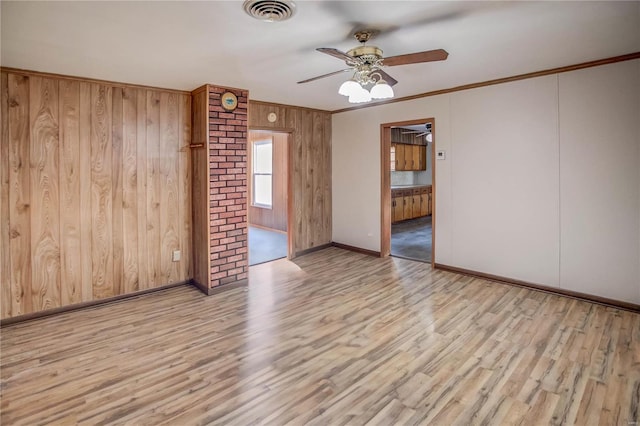 spare room with a ceiling fan, visible vents, crown molding, and wood finished floors