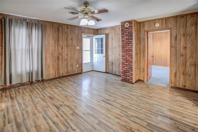 unfurnished room featuring visible vents, baseboards, ceiling fan, wood finished floors, and wood walls