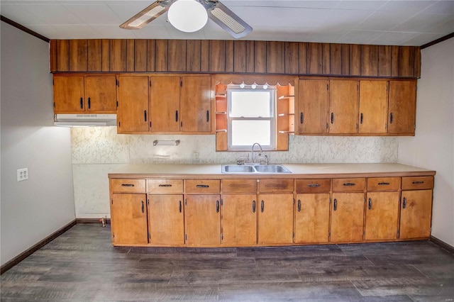 kitchen with brown cabinetry, a sink, and under cabinet range hood