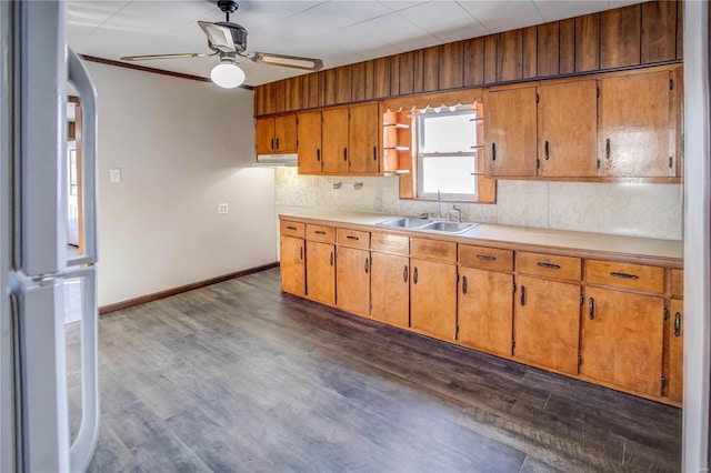 kitchen with brown cabinets, dark wood finished floors, light countertops, and a sink