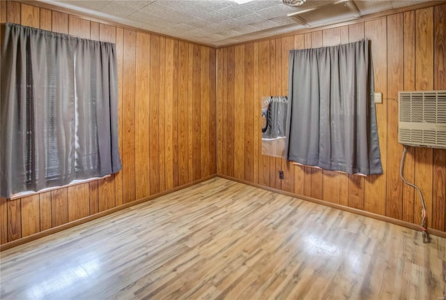 empty room with wooden walls, baseboards, wood finished floors, and a wall mounted air conditioner