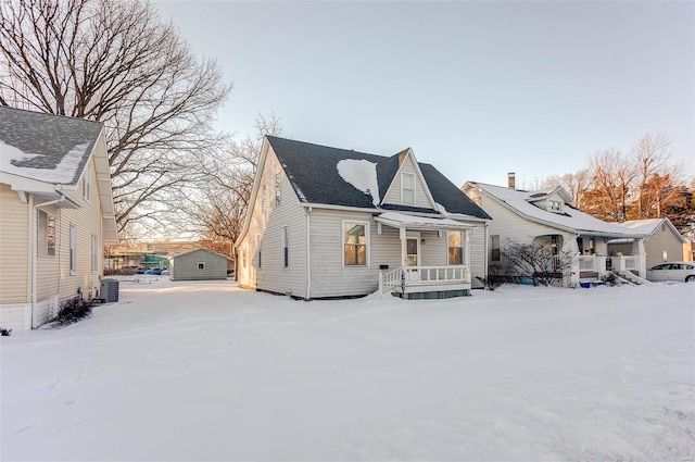 snow covered rear of property with central air condition unit and covered porch