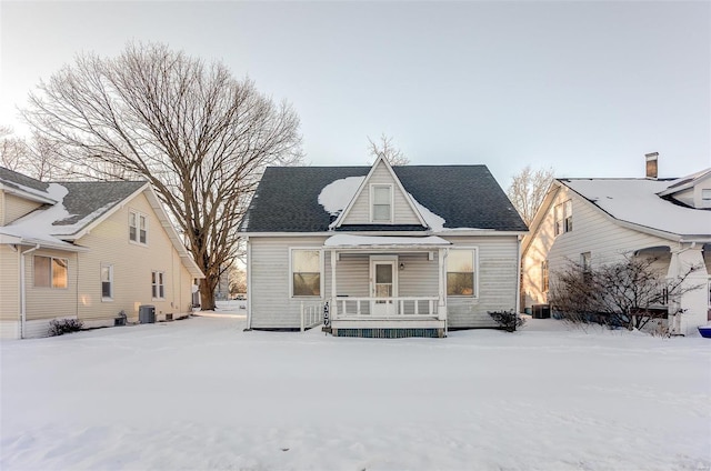 snow covered property with covered porch and central AC