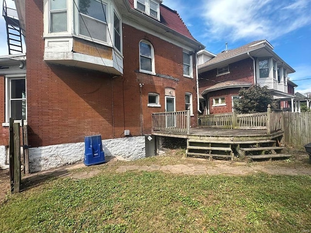 rear view of property featuring a lawn and a wooden deck