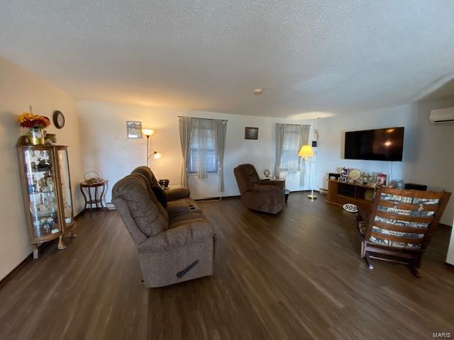 living room featuring a textured ceiling, a wall mounted air conditioner, and dark hardwood / wood-style floors