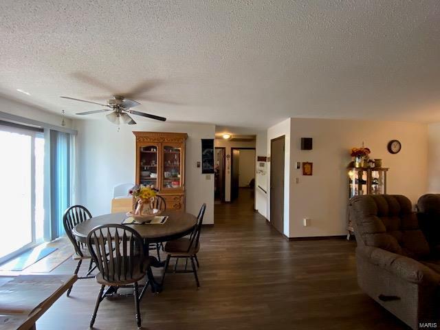 dining area featuring ceiling fan, dark wood-type flooring, and a textured ceiling