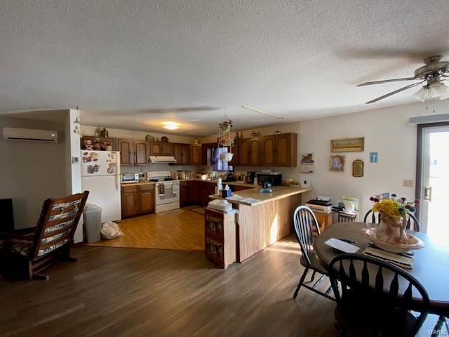 kitchen featuring white appliances, kitchen peninsula, dark wood-type flooring, ceiling fan, and a wall mounted air conditioner