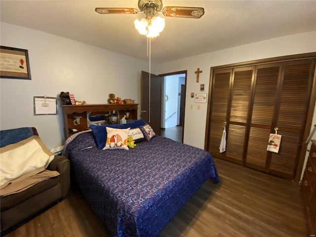 bedroom with ceiling fan, dark wood-type flooring, and a closet