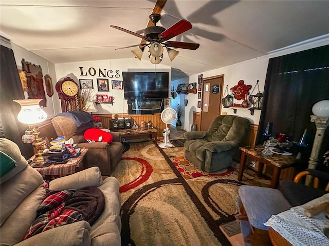 living room with ceiling fan, wooden walls, and vaulted ceiling