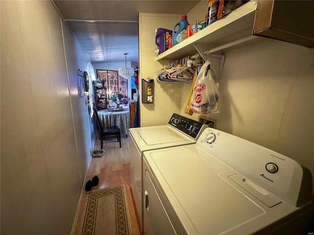 washroom with an inviting chandelier, light hardwood / wood-style floors, and separate washer and dryer