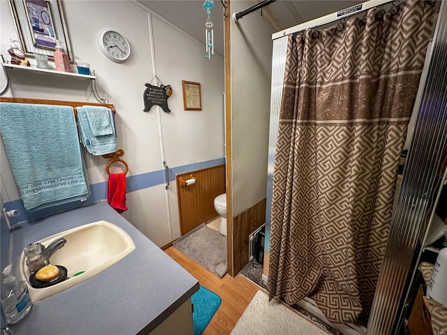 bathroom featuring wood-type flooring, toilet, vanity, and walk in shower